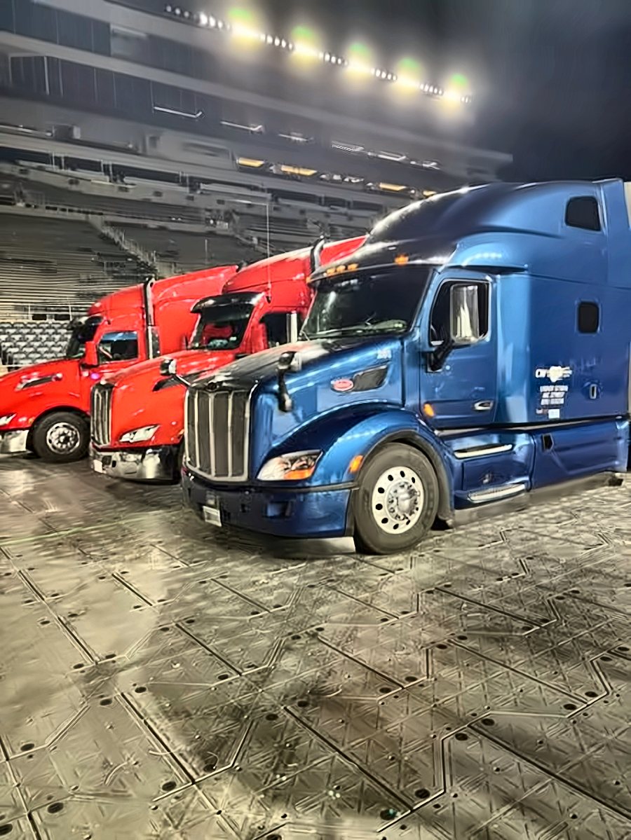 Blue CW Peterbilt inside a stadium at night